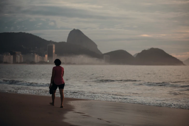 woman standing on beach watching the ocean with rock formations in background