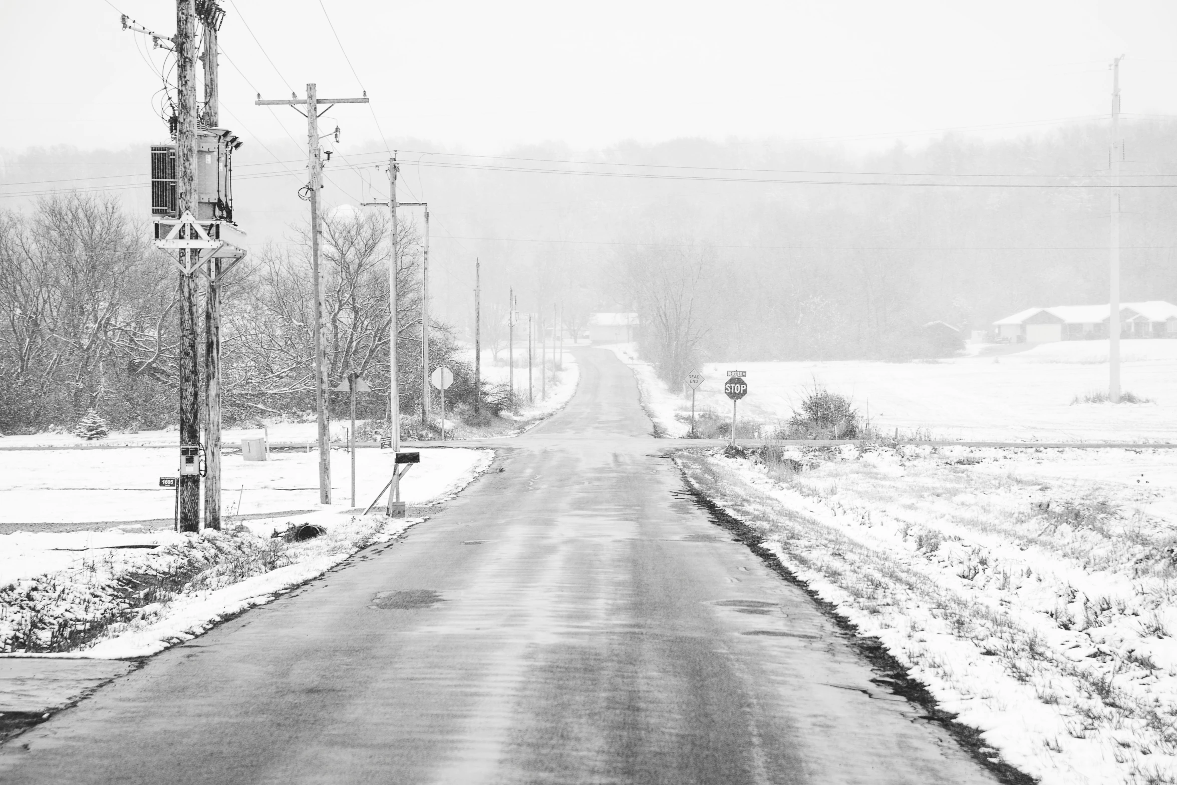 a road with snow on the ground near a forest