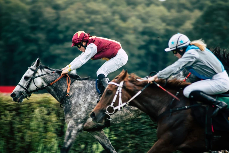 two people in jockeys racing horses along a course