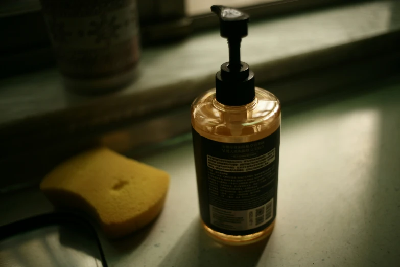 a bottle of liquid next to a sponge on a table