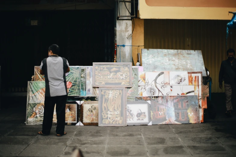 the man is standing in front of paintings outside