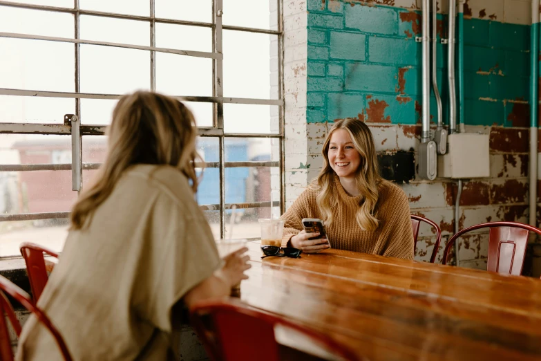 two women sitting at a wooden table next to each other