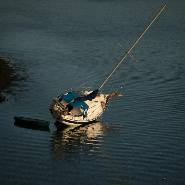 a small sailboat floating on the water with the mast out