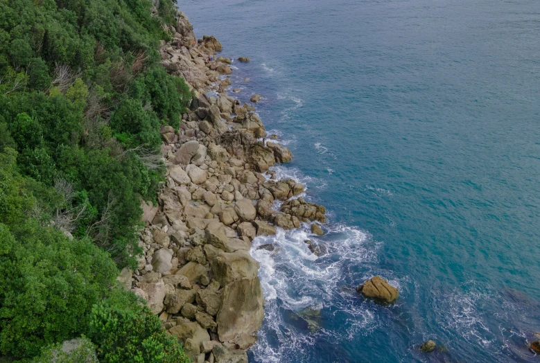 a boat is on the water next to a rocky shoreline