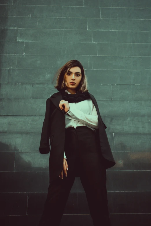 the woman poses in front of a gray wall