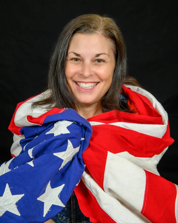 a lady holding an american flag and smiling