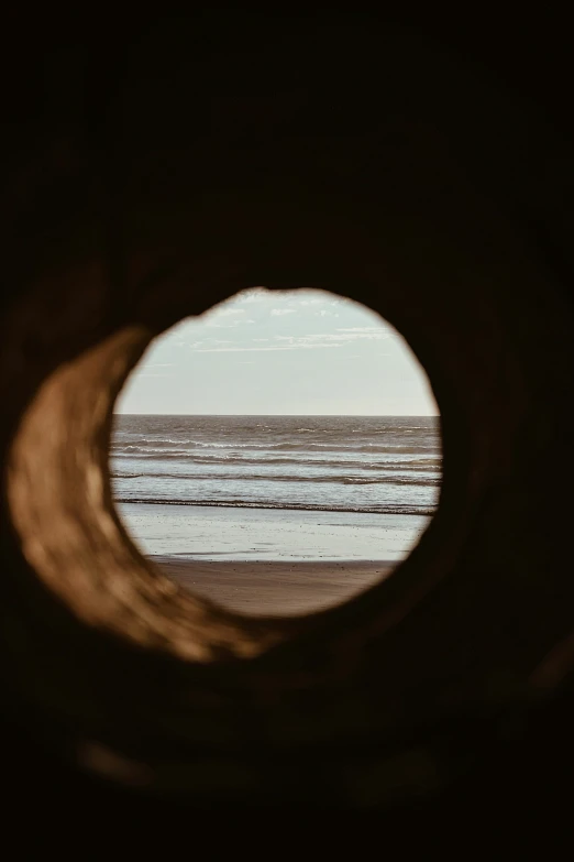 the view of a beach from inside a tunnel