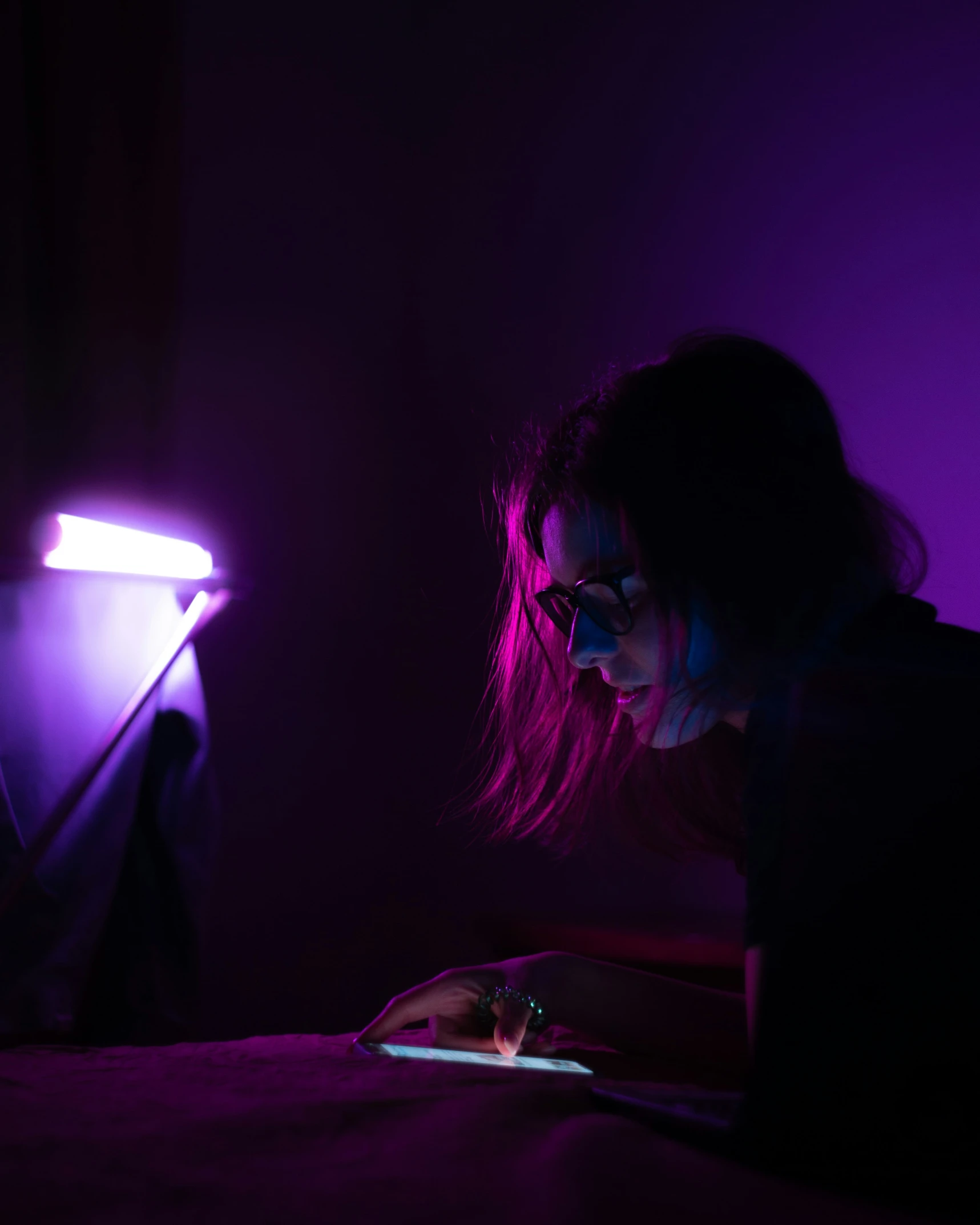 a girl is sitting in bed using a laptop computer with the light on