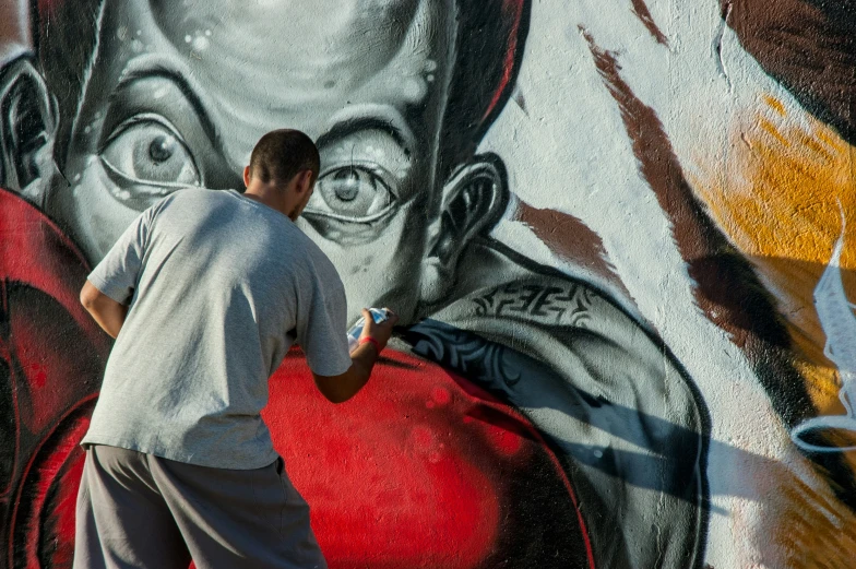a man painting on a graffiti wall with red ball