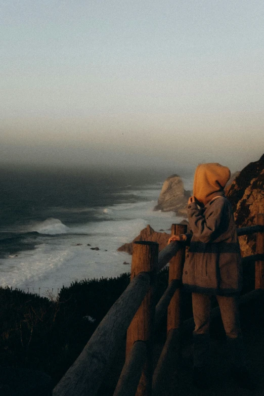 person standing on cliff overlooking ocean on clear day