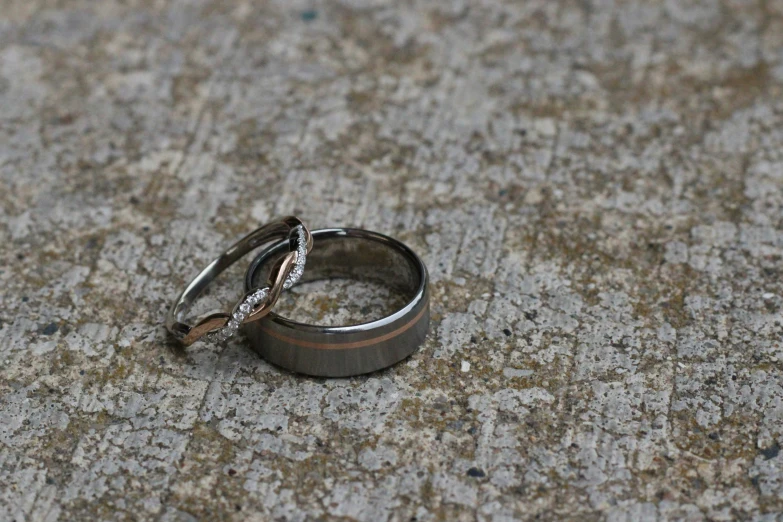 two rings on cement and one has diamond ring in middle