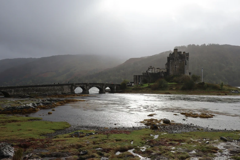 a beautiful stone bridge across a river in front of a castle