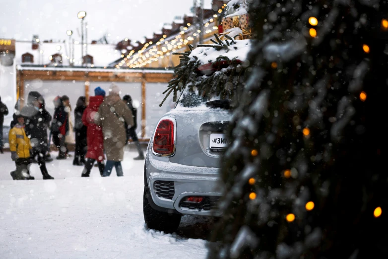 a car is parked in the snow and people are walking around the house