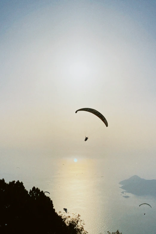 the silhouette of two people para - sailing against a gray sky