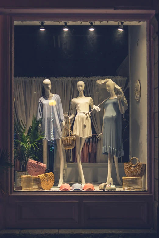 three mannequins in a window display, with different styles and colors