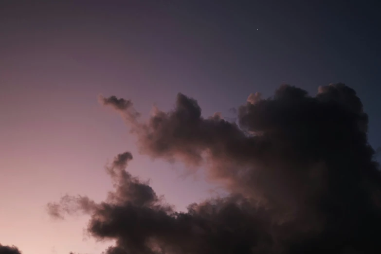 several clouds in the sky with an airplane flying by