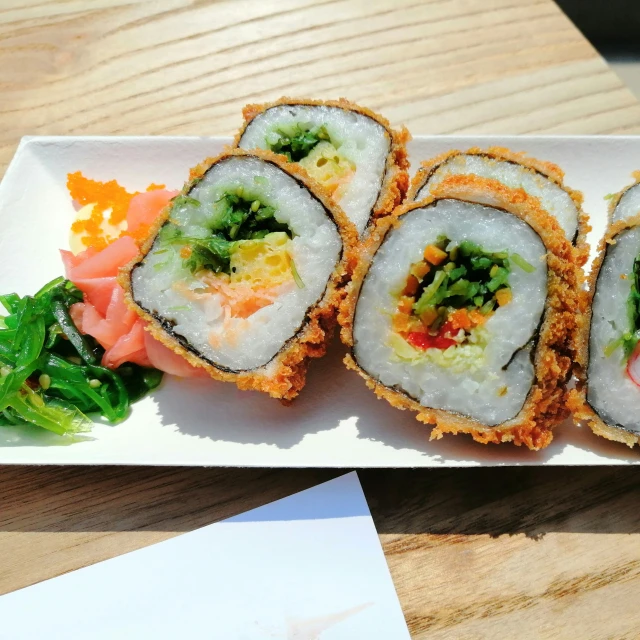 a white plate topped with sushi and veggies