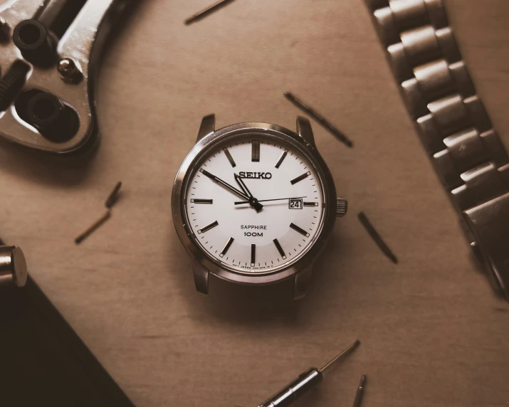 a watch sitting next to a pair of pliers