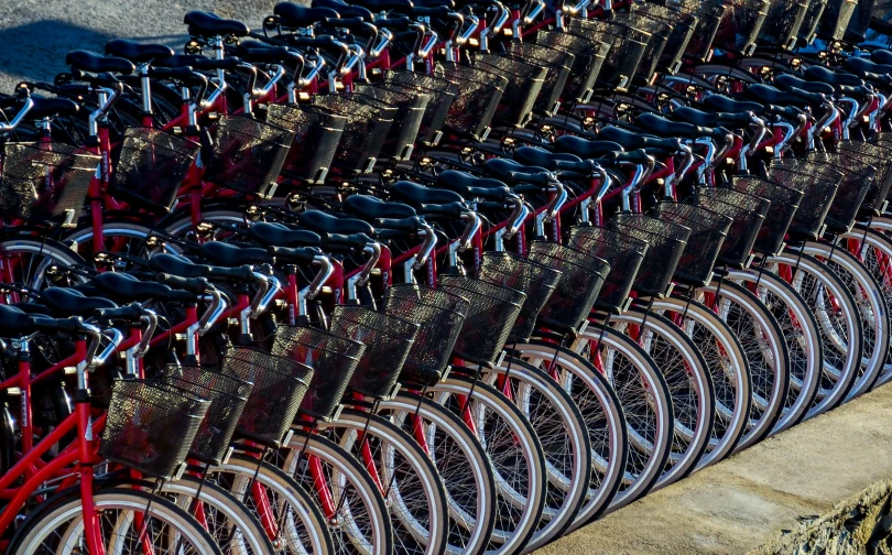 a row of many bicycles sitting in a parking lot