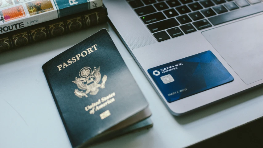 a passport is next to an open laptop computer