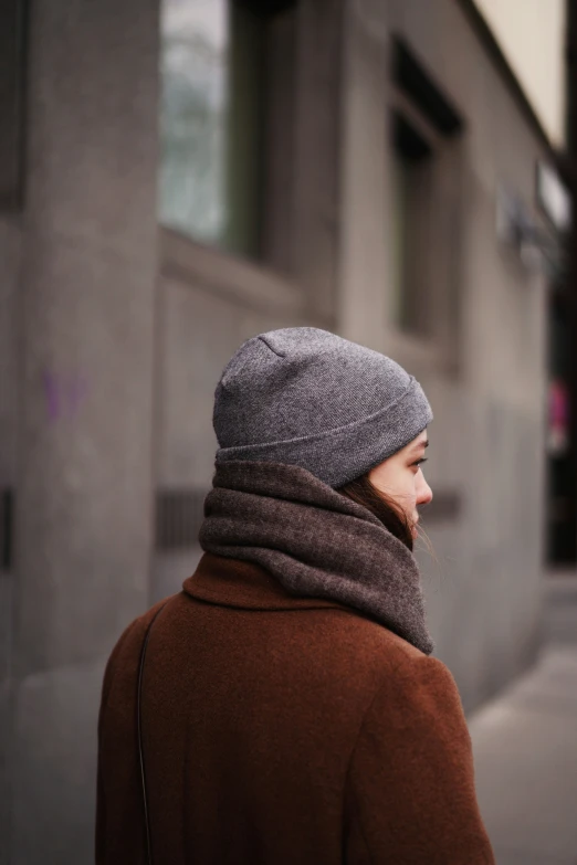 a person wearing a hat walking in front of a building