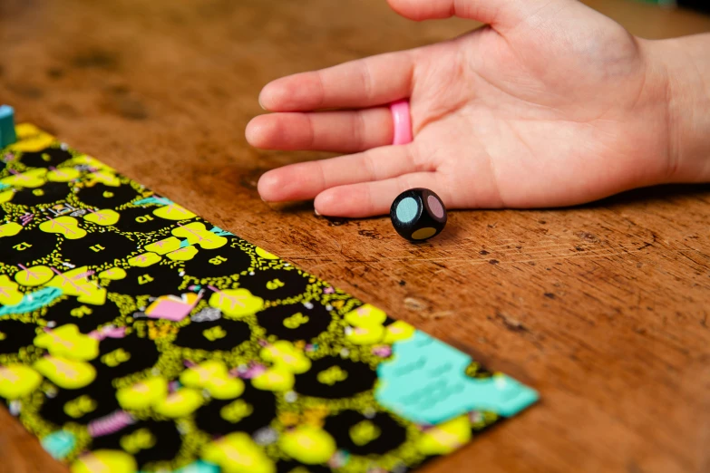 a hand sitting on top of a wooden table next to a fabric