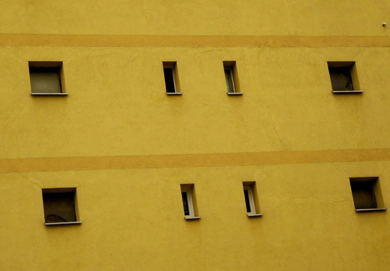 yellow wall with four small windows that are missing