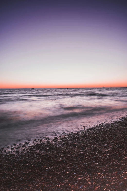 the horizon and the shoreline are illuminated in purple, pink and orange