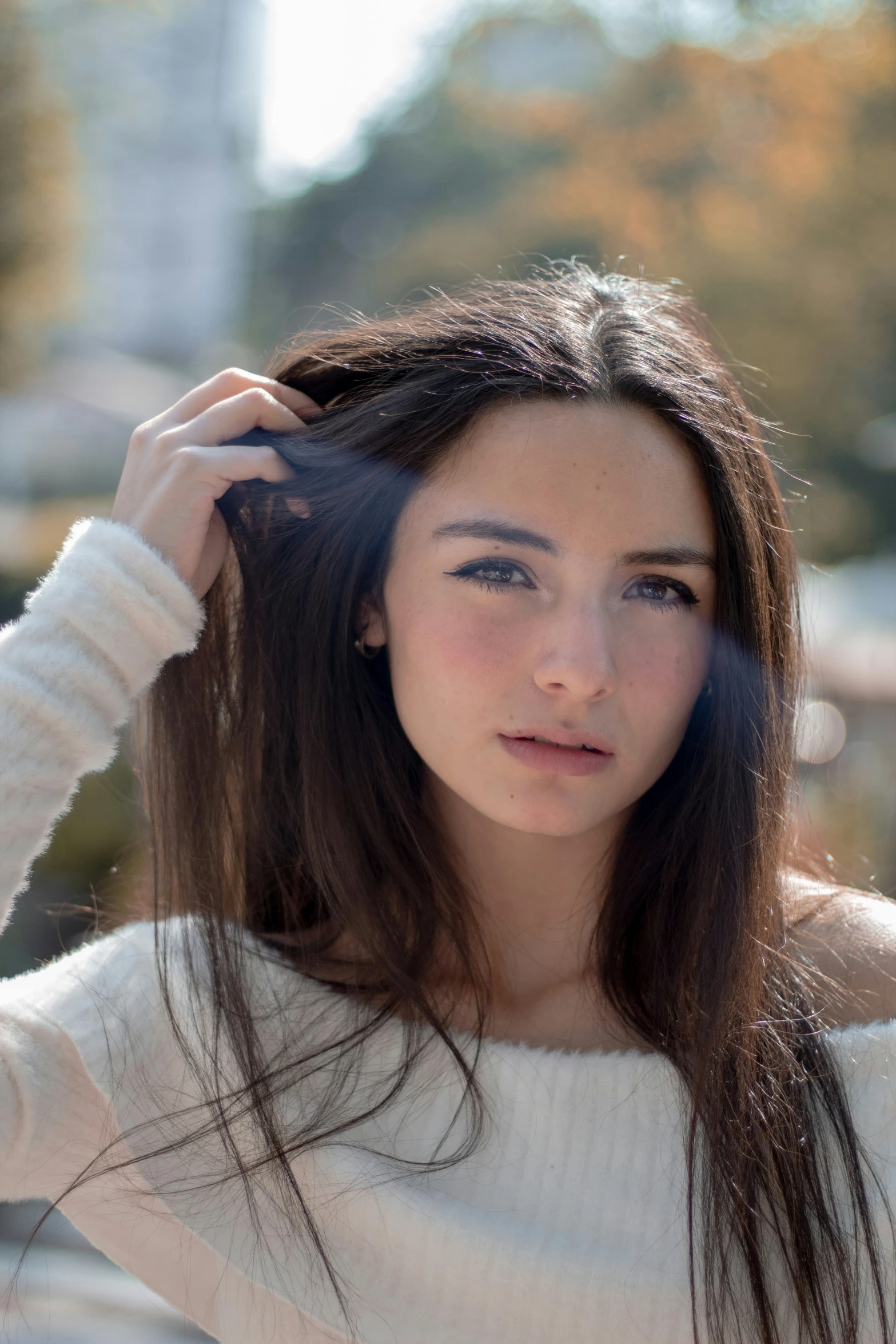 a woman in a sweater poses on the sidewalk