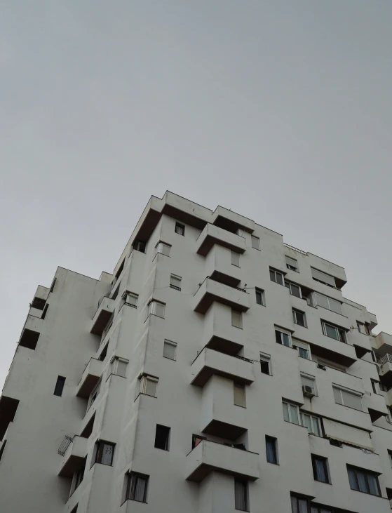 an architectural white building with balconies near a street