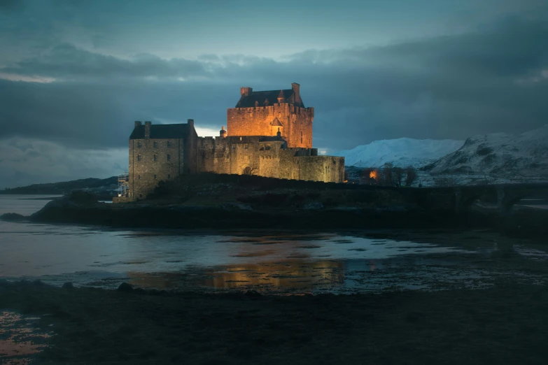 a medieval castle sits on a rock surrounded by snow