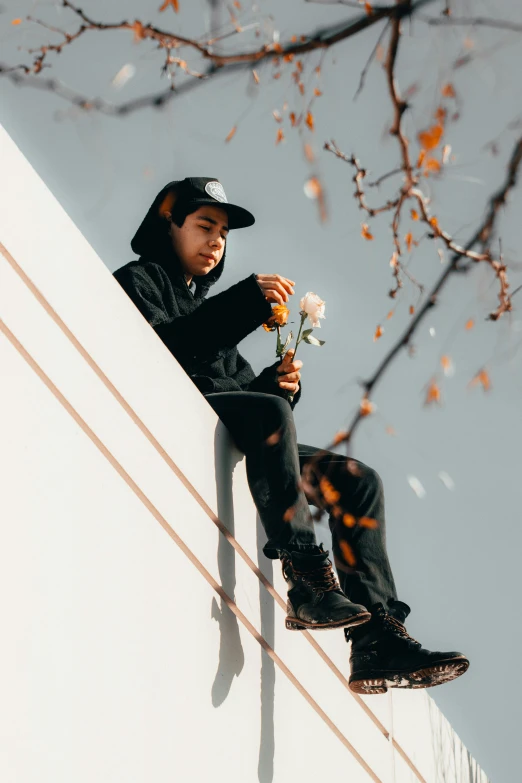 the young man sits on top of the tall wall