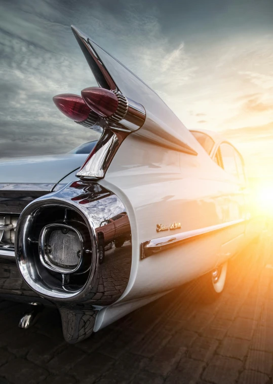 the back end of a classic car with a sun flare in the background