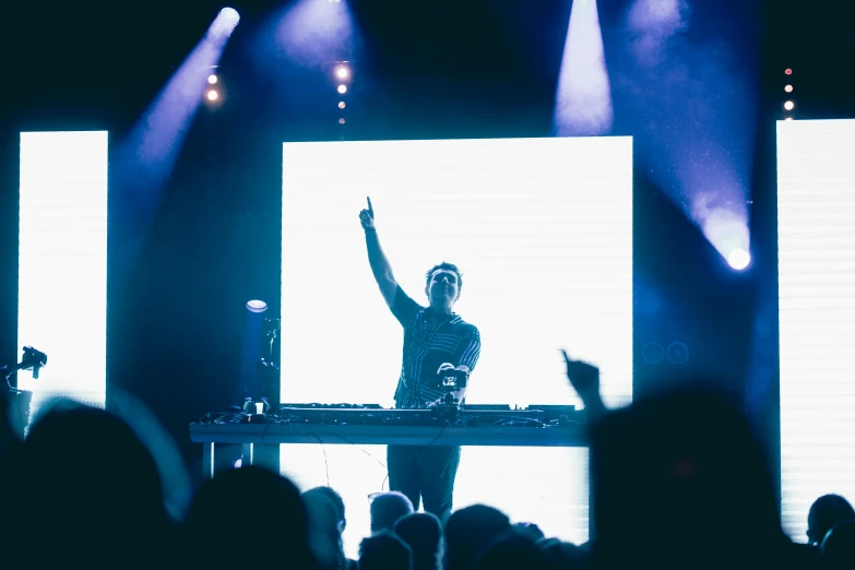 a dj is holding his hands up in the air