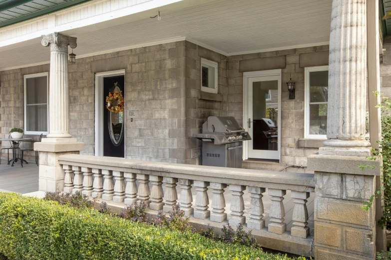 a grey house with large pillars and stone front porch