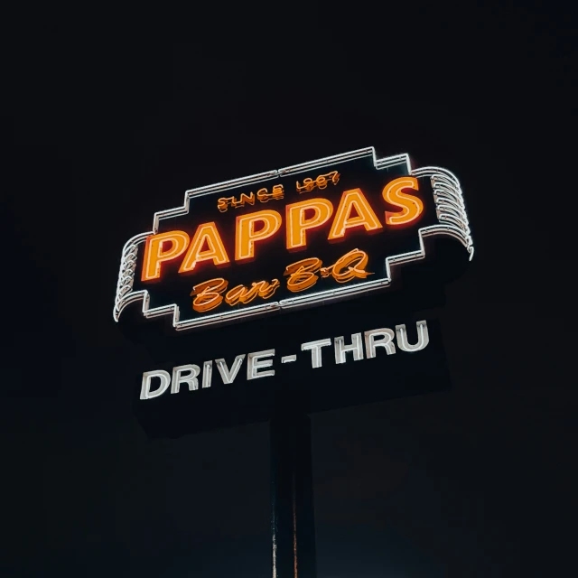 a sign for papa's drive thru, lit up at night