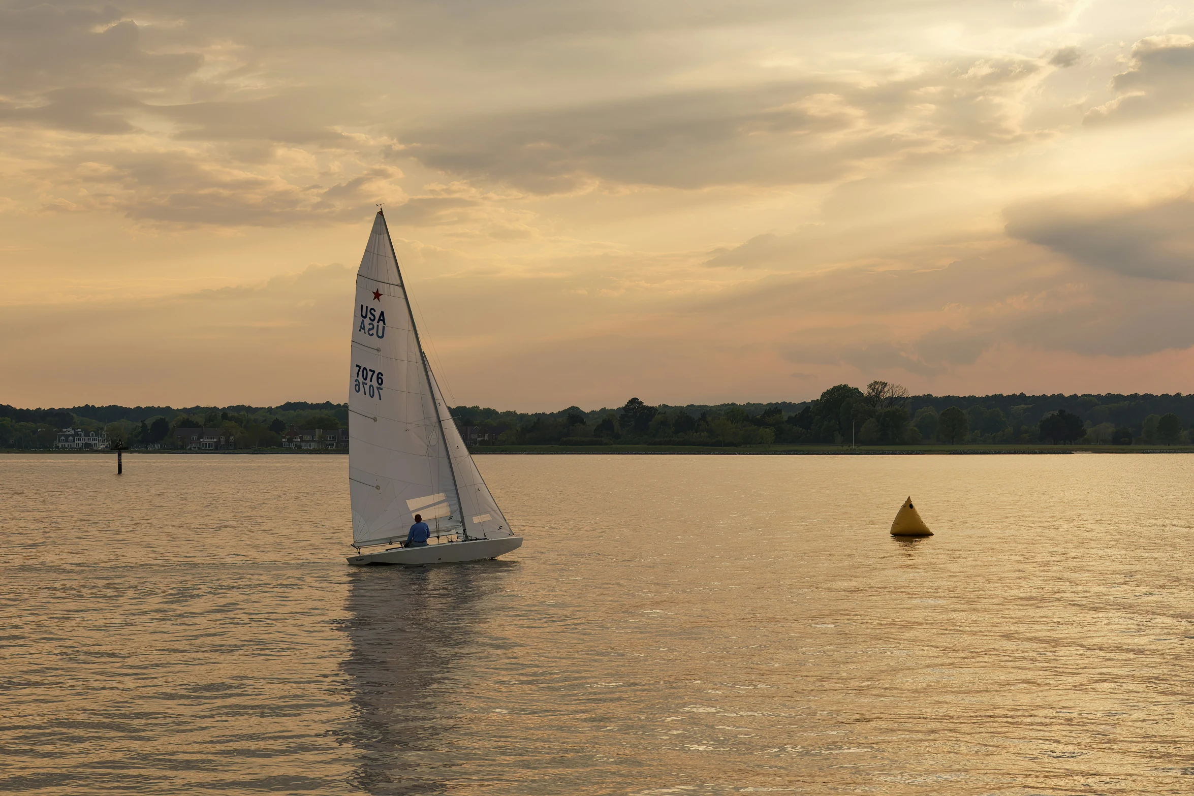 a sailboat sailing on the water at sunset