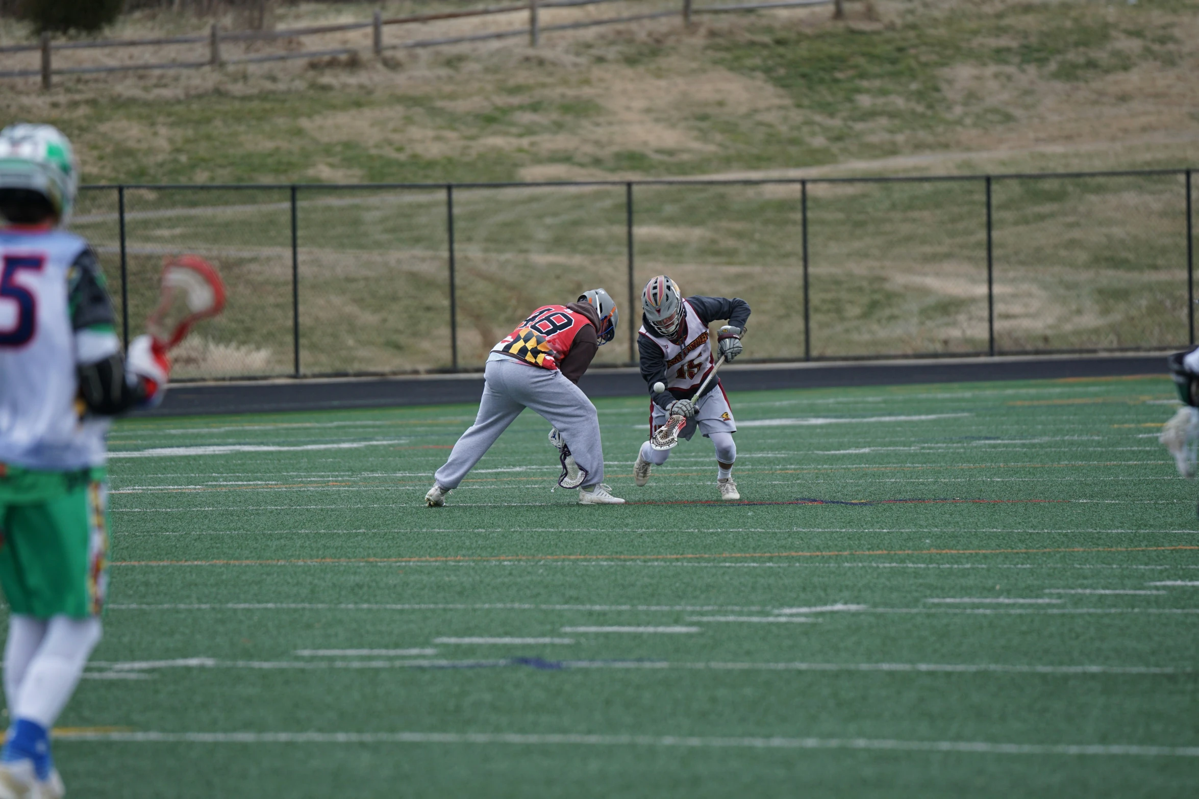 three guys on a field playing lacrosse