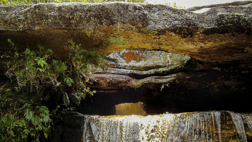 a waterfall flows through a large rock face