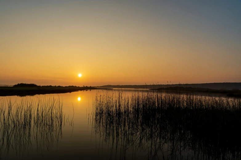 the sun setting behind an outcropping of water