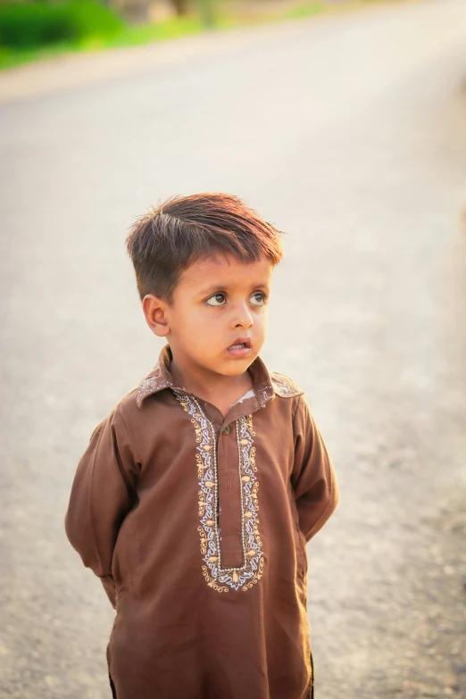 a boy stands on the road in front of a camera