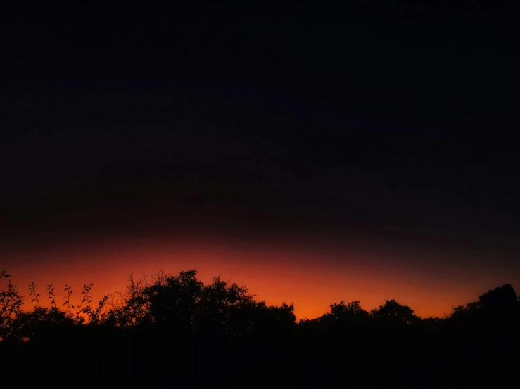 a sunset view from a distance with the sun partially obscured by clouds