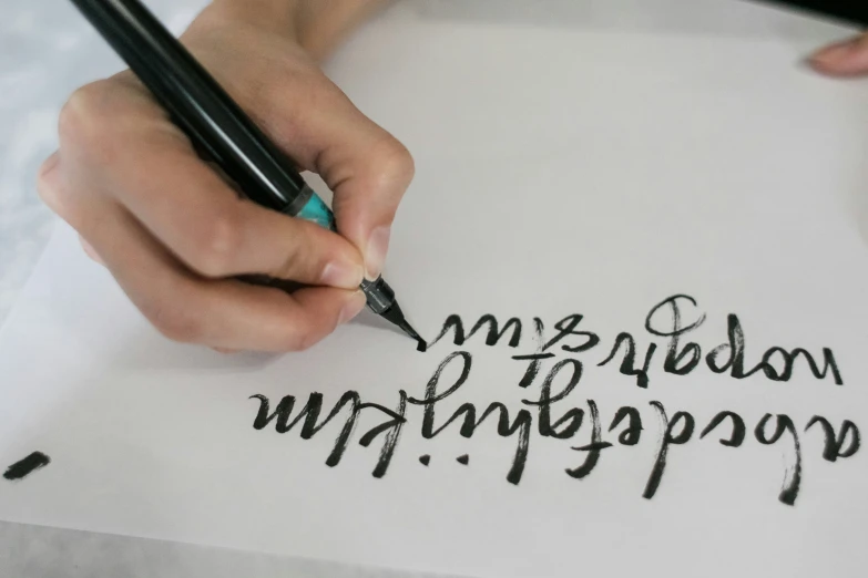 someone writing on paper with a fountain pen
