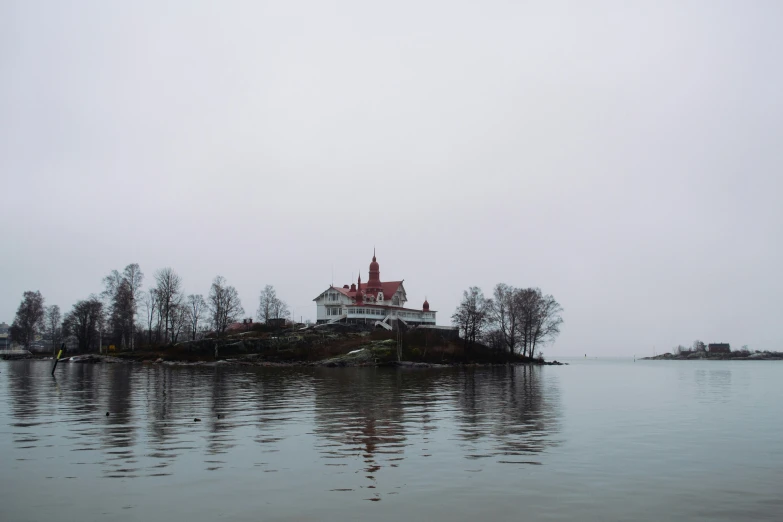 the island is surrounded by water and has a red roofed house on top