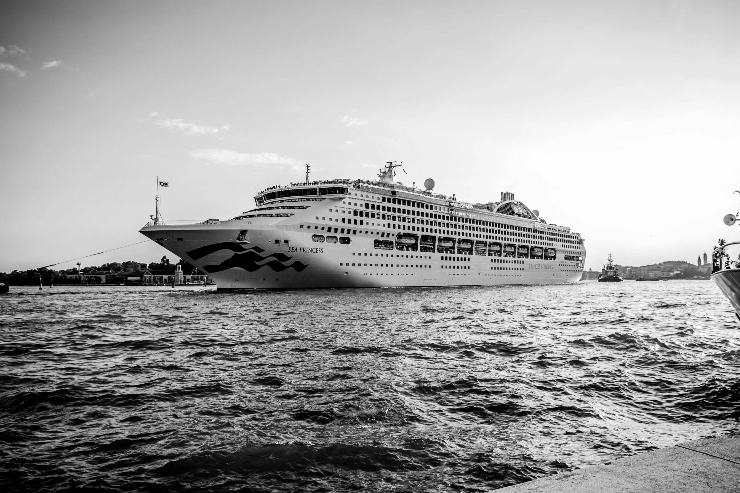 large cruise ship in port while other boats pass by