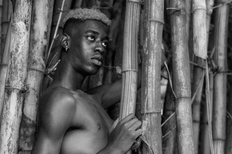 a boy is posing in front of some bamboo