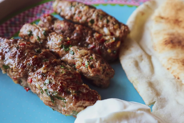 meat with sauce and bread on plate near small pita bread