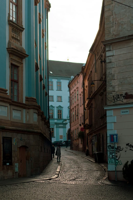 an image of two people walking down a narrow street