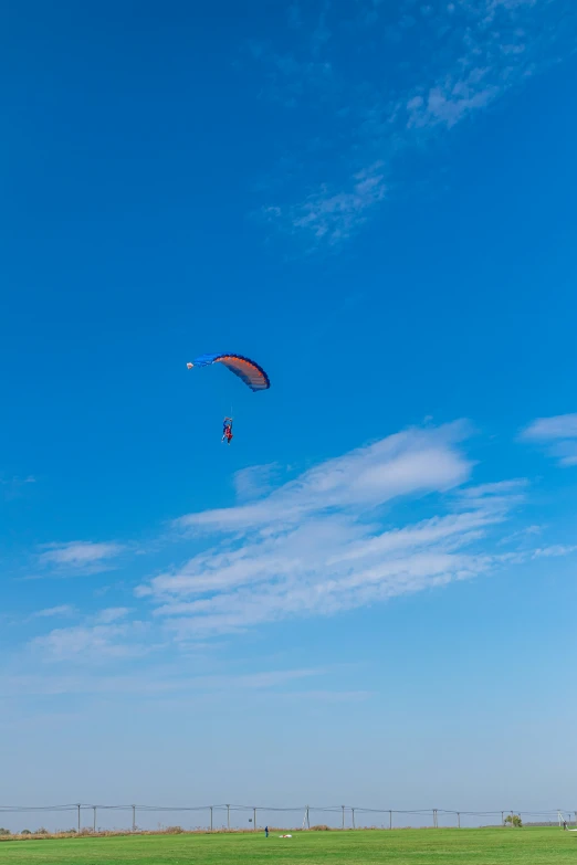 a large green field with a kite flying above