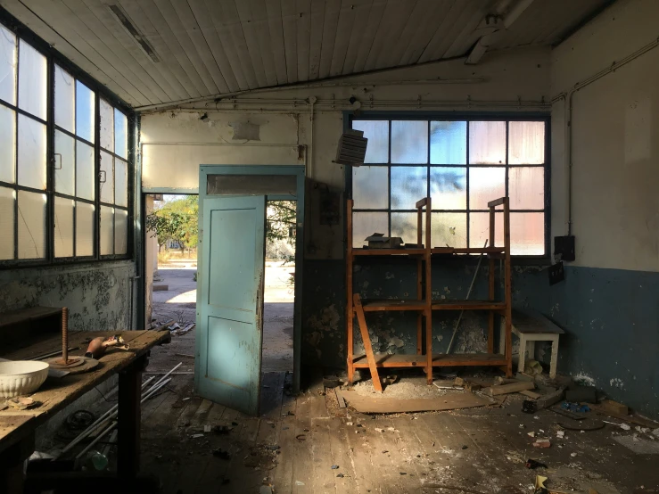 a dilapidated room with a blue door and shelves